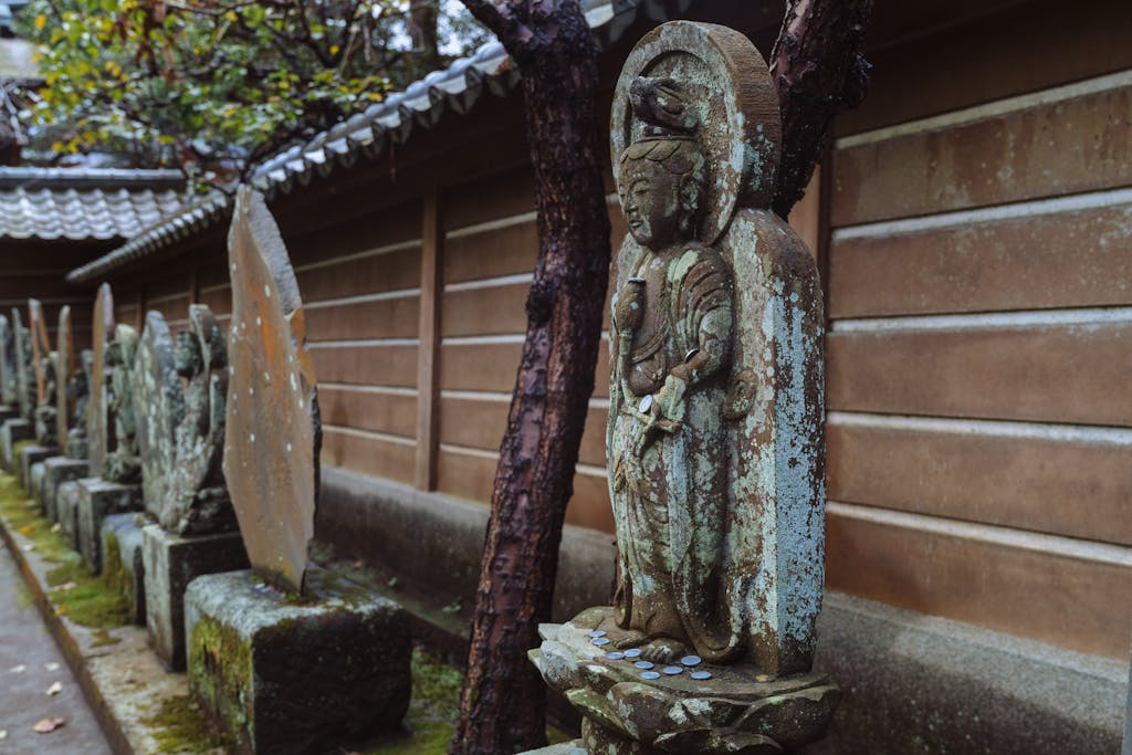 Close-up of weathered stone Buddha statues in a serene Kamakura temple garden, showcasing cultural heritage.