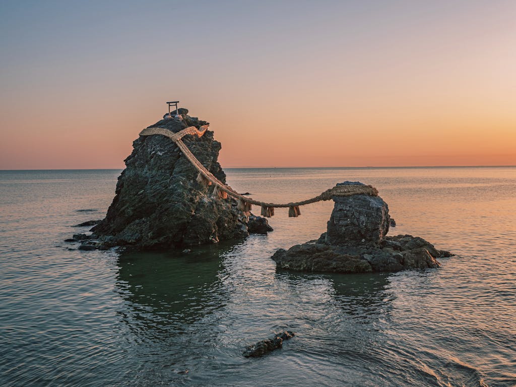Photograph of the Meoto Iwa sacred rocks at sunrise, a spiritual site in Japan's ocean.