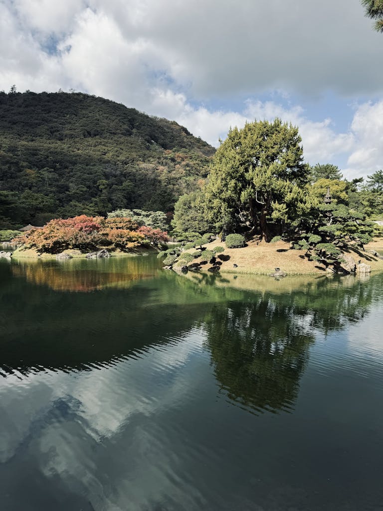 Serene autumn landscape of Ritsurin Garden in Takamatsu with mountain reflections.