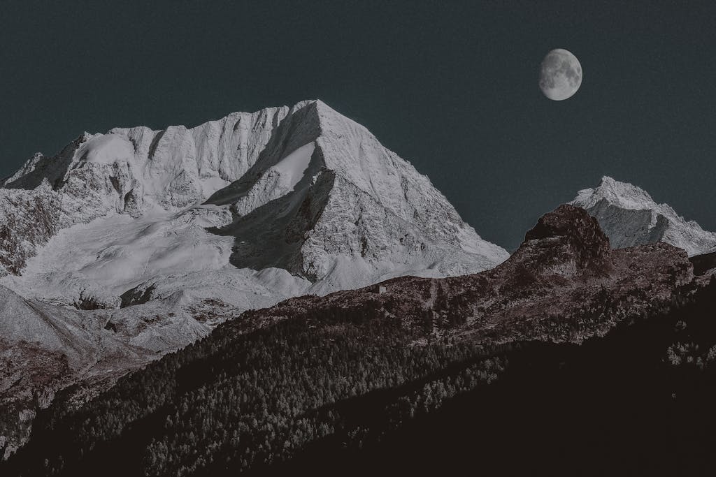 Breathtaking view of a majestic snow-capped mountain under a clear moonlit night sky.